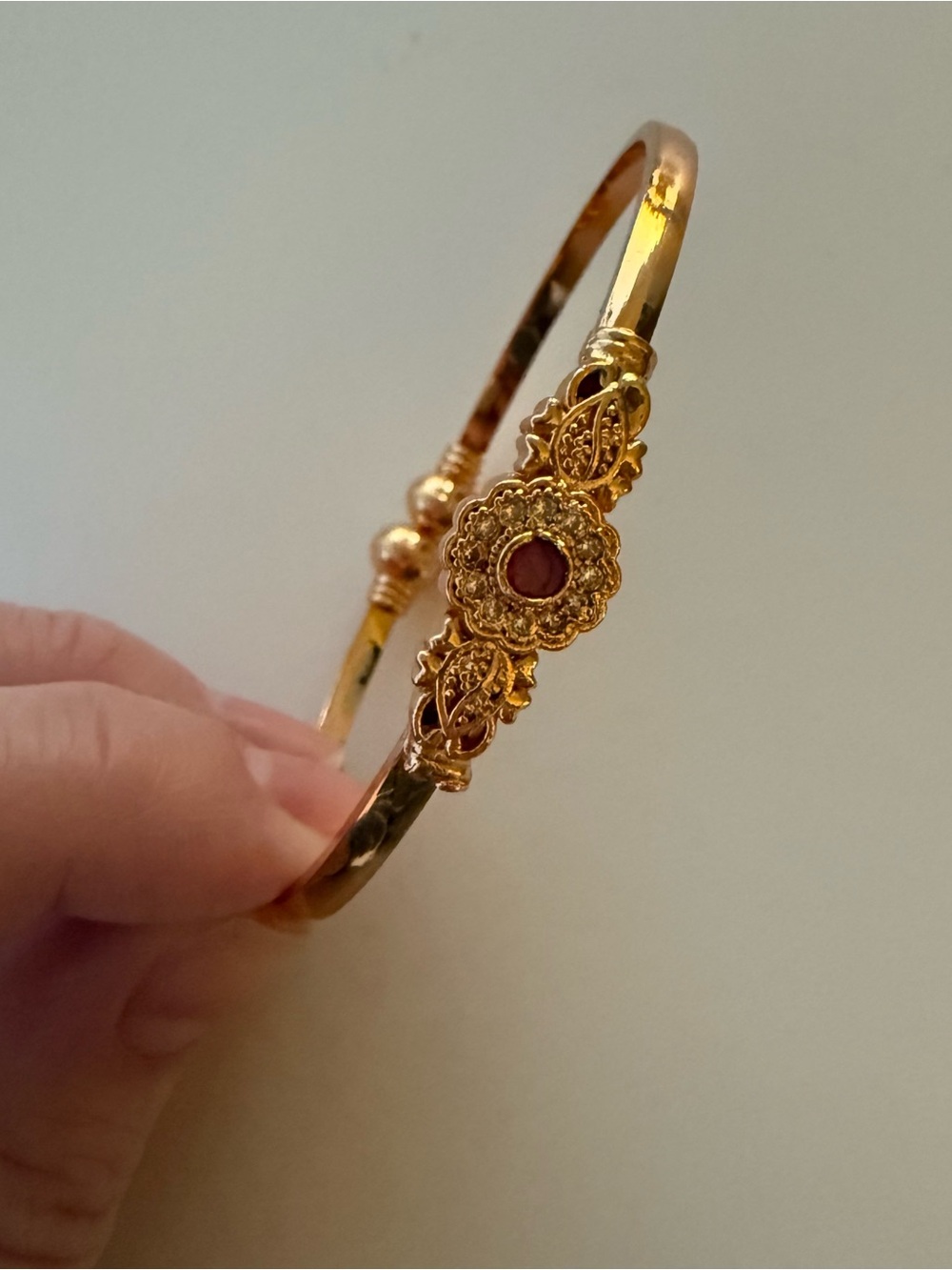 Gold bangle with red gemstone flower